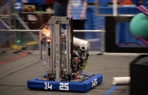  Team 1425’s robot for the 2025 Reefscape season zooms across the field, attempting to place a piece of coral on the violet reef. The drive team is entirely focused on their next move and how to win the match.